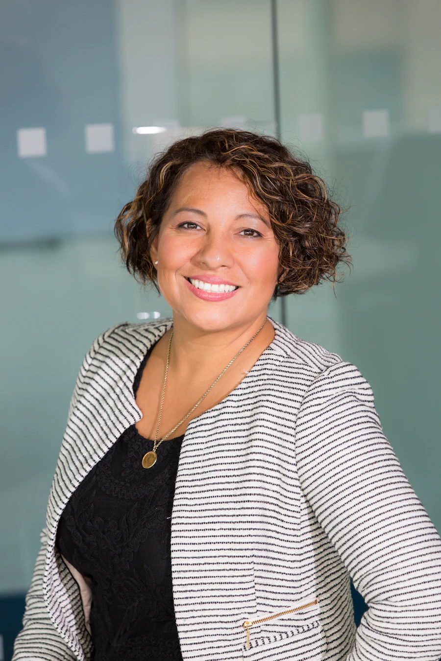 A smiling woman in a checked jacket in an office