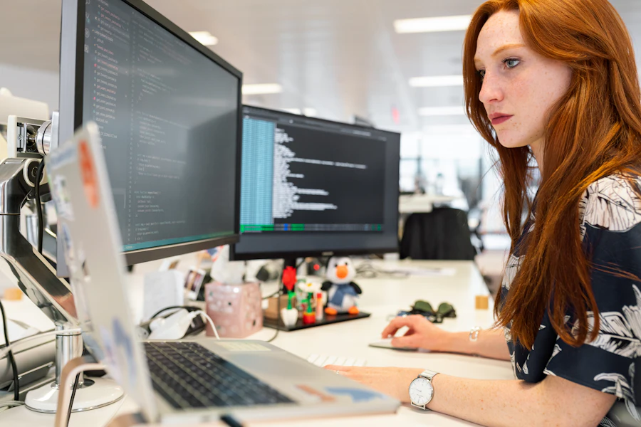 A woman working at two computer monitors