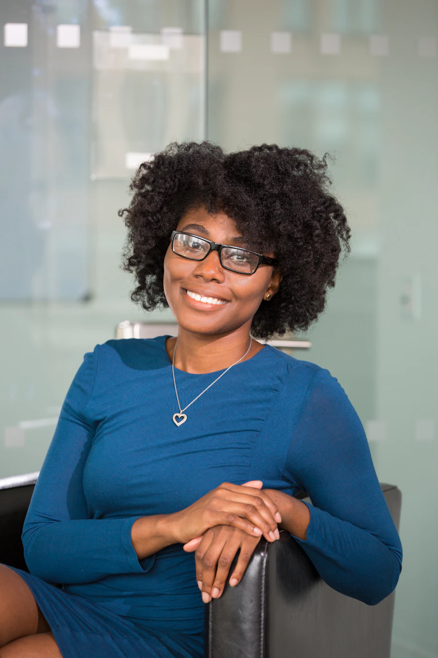A smiling woman wearing glasses and a blue top