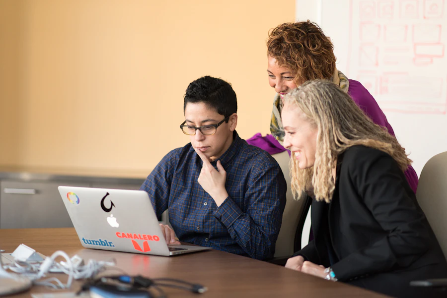 Three colleagues reviewing a laptop together