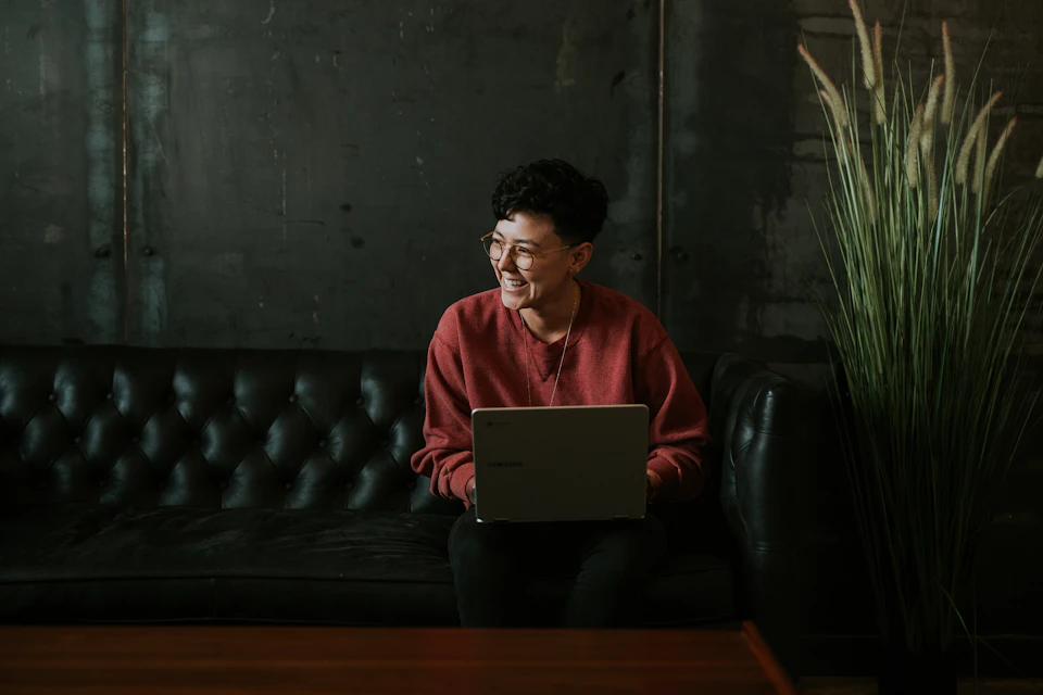 A smiling professional with a laptop on a sofa; illustrative stock photography