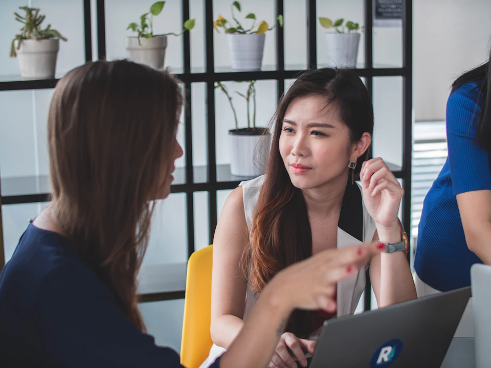 Colleagues discussing work in an office; illustrative stock photography, not an incident or allegation