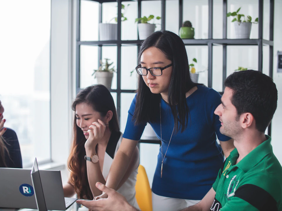 Colleagues collaborating around a laptop; illustrative stock photography