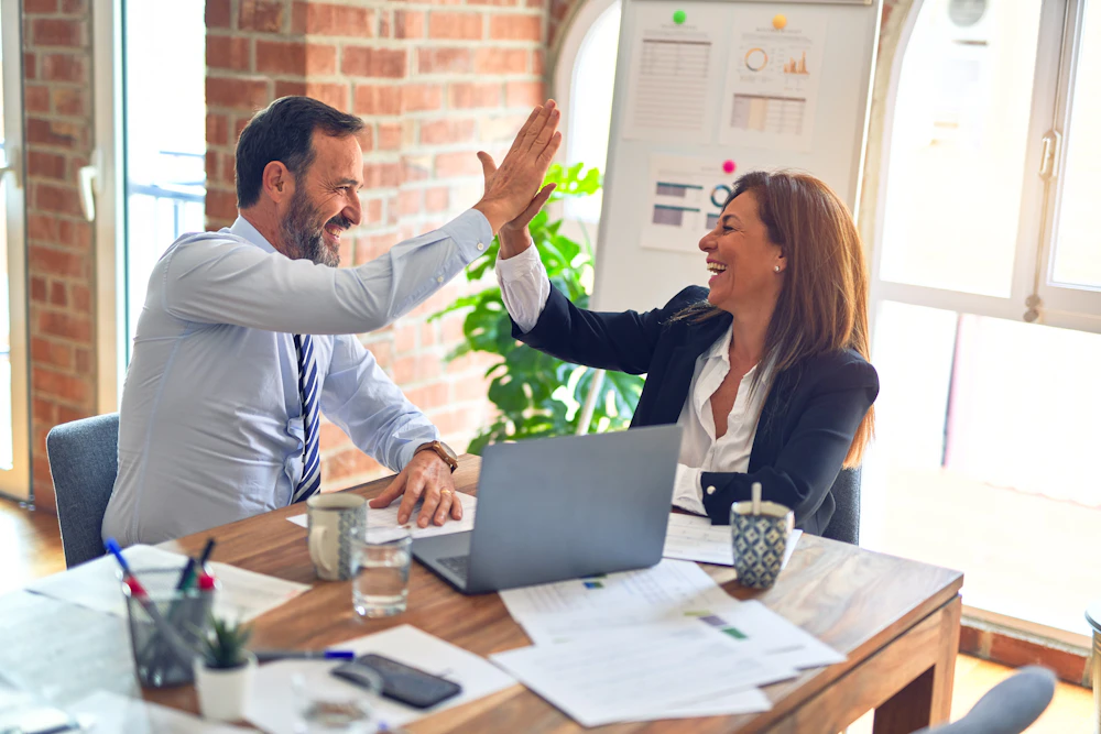 Colleagues discussing work around a table; illustrative stock photography